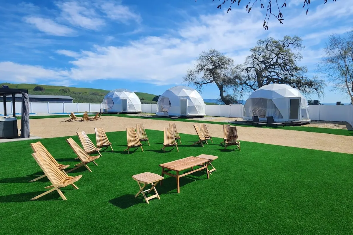 Wooden lounge chairs facing the three domes