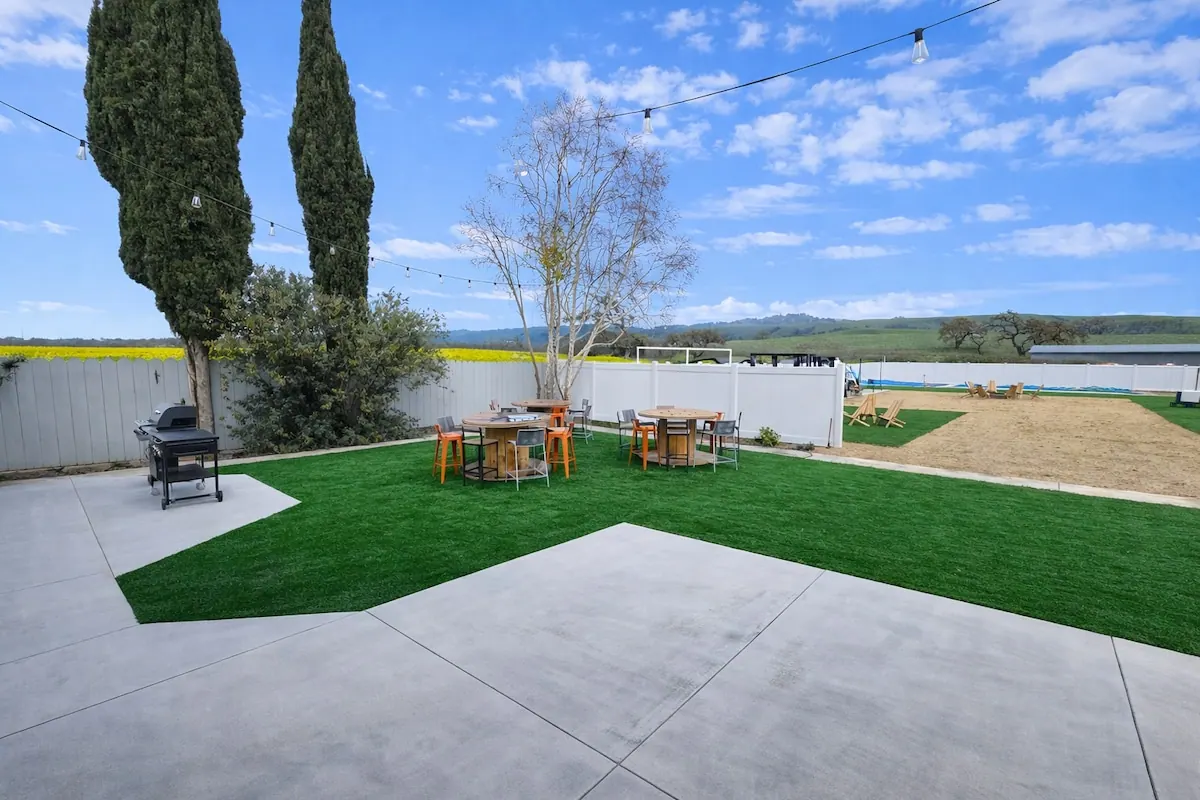 Backyard lawn with bar tables and cypress trees